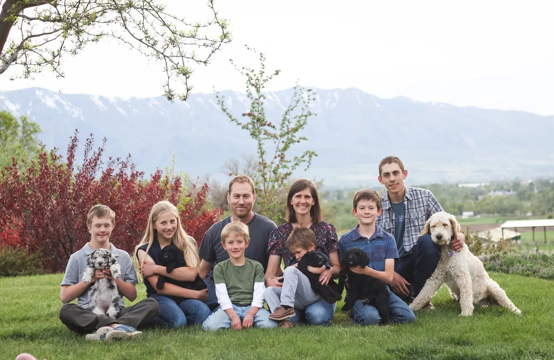 The Downs family and their dogs on the farm lawn with the mountains behind